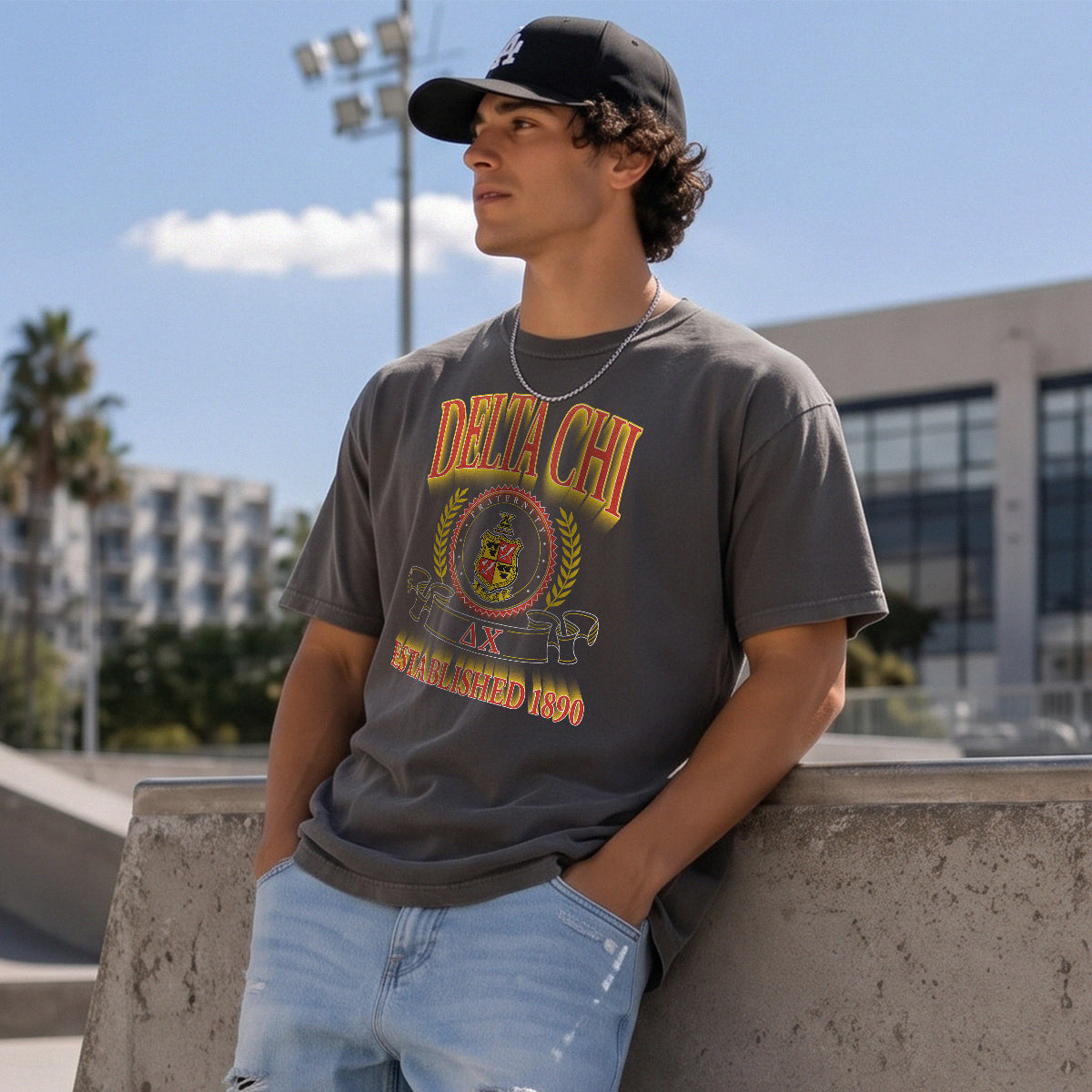 College-aged male wearing the fraternity Collegiate Crest Graphic Tee in charcoal grey, featuring vintage Delta Chi crest artwork on campus.